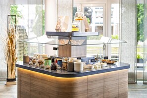 A breakfast bar with a glass enclosure, various food items, and a sign indicating 'cereal corner'.