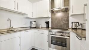 A modern kitchen with white cabinets, stainless steel appliances, and a built-in oven.