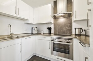 A modern kitchen with white cabinets, stainless steel appliances, and a built-in oven. - Best Western Plus Hotel Papenburg (Papenburg)