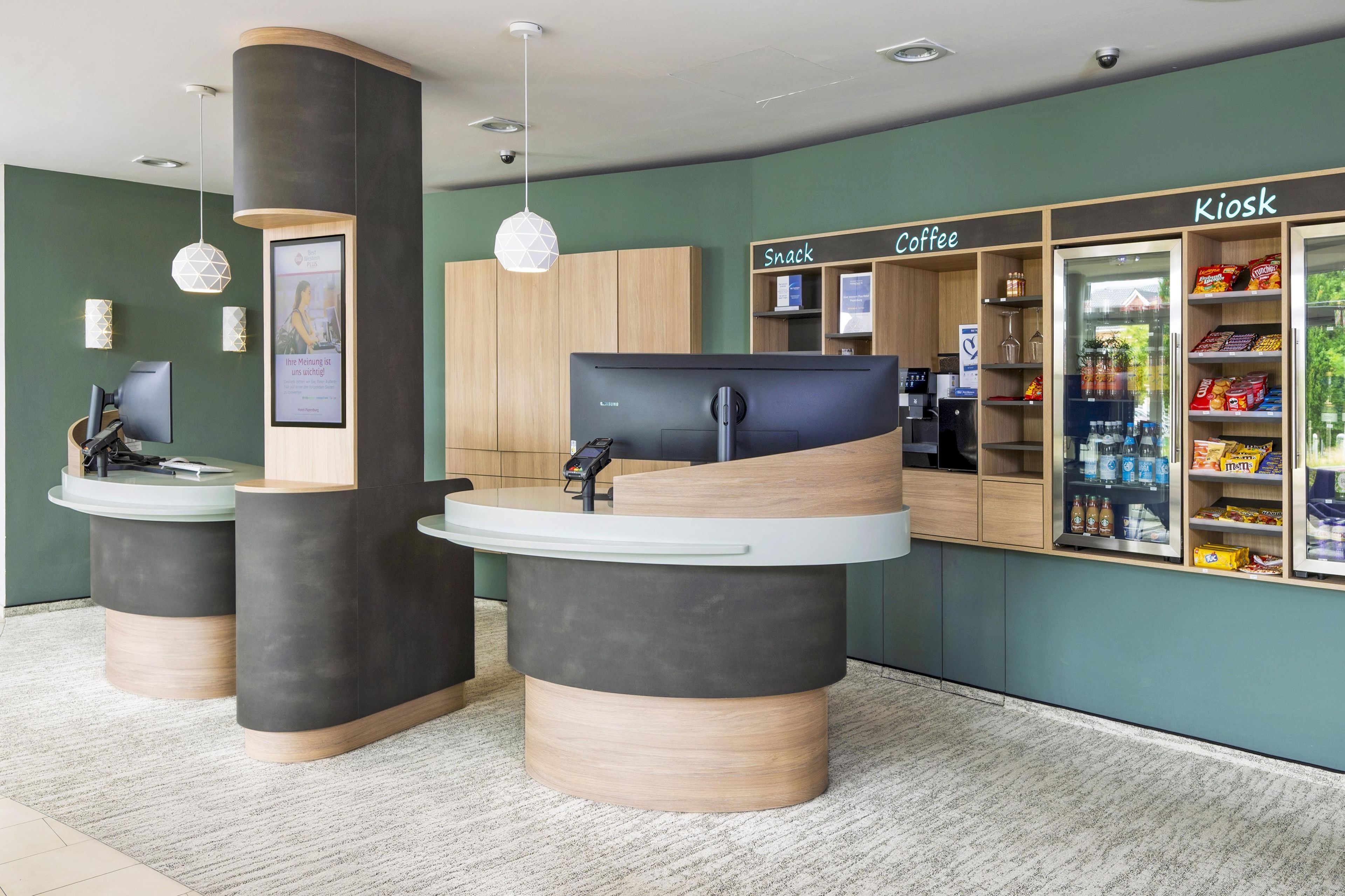 Un espace d’accueil comprenant un comptoir, un ordinateur et un kiosque portant l’inscription « Kiosk Coffee ».