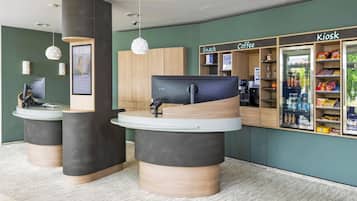 Un espace d’accueil comprenant un comptoir, un ordinateur et un kiosque portant l’inscription « Kiosk Coffee ».