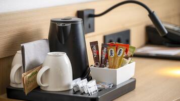 Een koffiehoek met een koffiezetapparaat, een mok en een bak koffiecups.