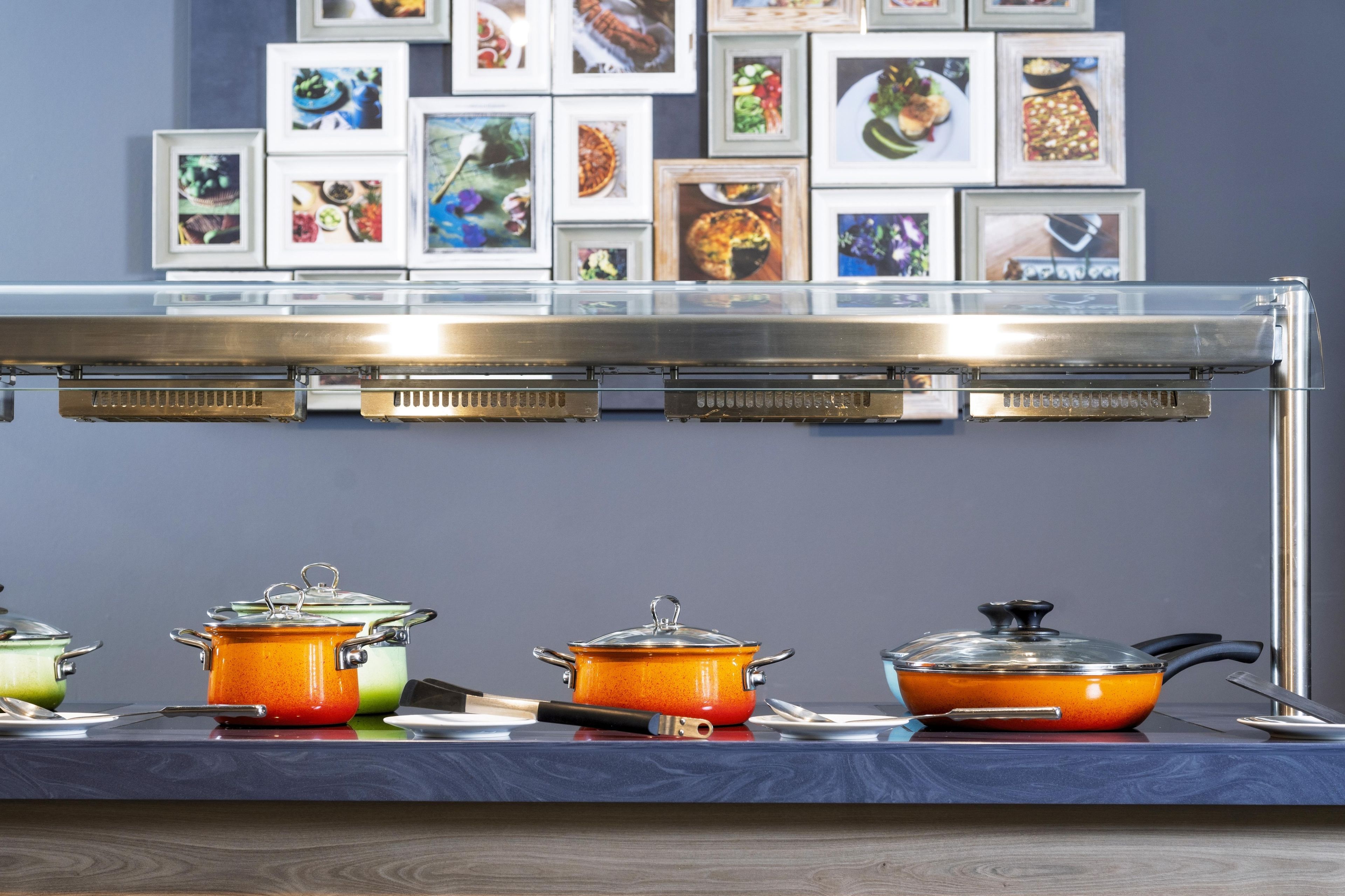 A buffet setup with multiple food service stations, a selection of dishes, and a wall decorated with framed food photographs.