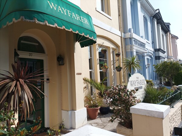 A hotel entrance with a green awning labeled "WAYFAKER," a sign indicating "VACANCY," and a "THE WAYFAKER" sign.