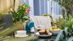 Une table dressée avec une théière, des tasses, des muffins et des fruits.