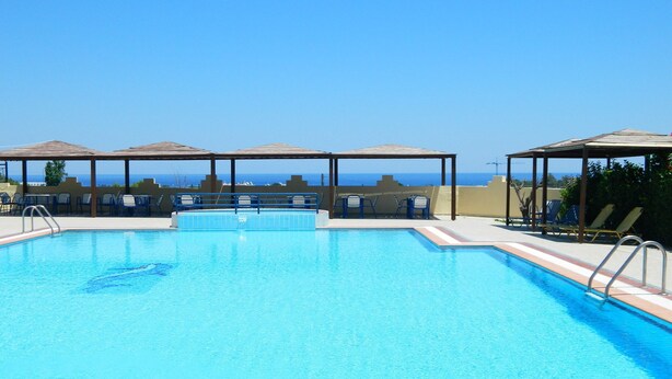 Une piscine d’un bleu éclatant, dotée de chaises longues et de parasols, et offrant une vue panoramique.