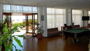 Un espace intérieur vaste et accueillant, doté d’une table de billard, de sièges confortables et de grandes fenêtres offrant une vue sur l’extérieur.