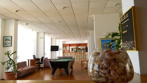 Une pièce spacieuse comprenant une table de billard, un coin bar et un espace détente avec un canapé et des fauteuils.