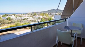 Un balcon donnant sur la ville et les collines, une table blanche et deux chaises.
