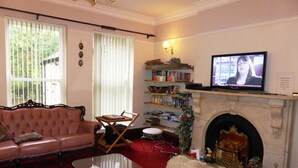 A living room with a pink sofa, a glass coffee table, a fireplace, and a television. - The Old Vicarage Hotel (Leeds)