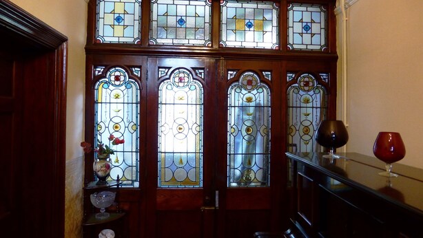 A fire exit sign above a set of stained glass doors with a staircase leading down. - The Old Vicarage Hotel (Leeds)