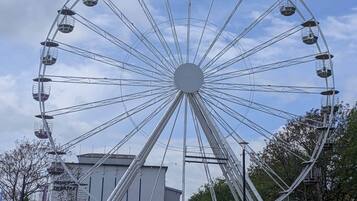 A large Ferris wheel with multiple cabins, a building labeled "Prince of the City Theatre," and a stone wall in the foreground.