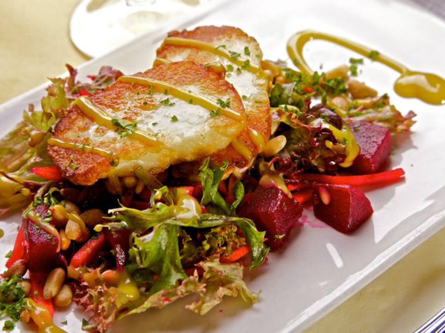 A plated dish with a variety of vegetables and a piece of bread.