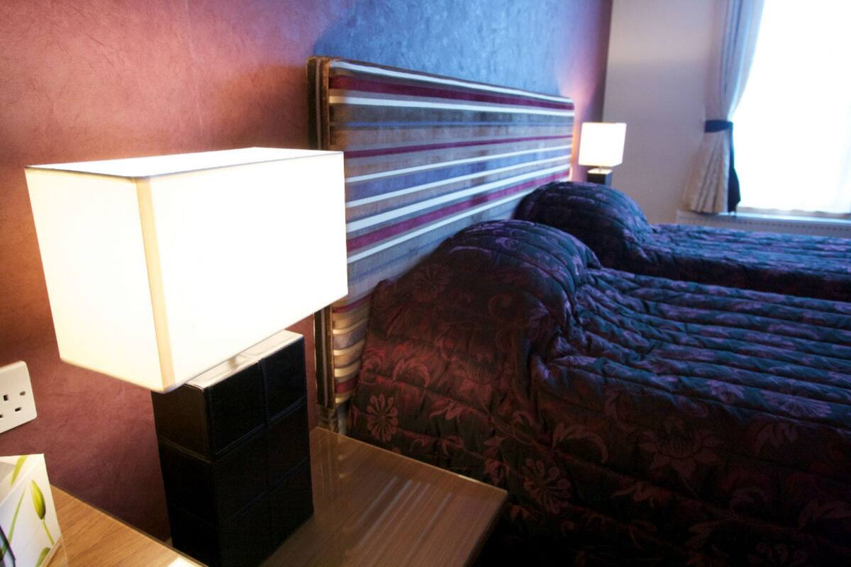 A hotel room with a large bed, a bedside table with a lamp, and a nightstand.