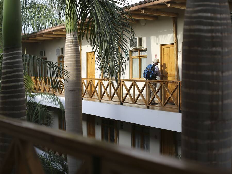 A two-story building with a balcony, wooden railings, and a person with a backpack.