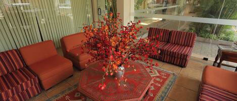 Una habitación con un gran ventanal, un tapete rojo estampado y muebles a rayas.