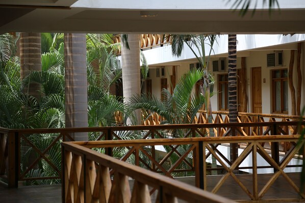 A covered outdoor area with wooden railings and palm trees.