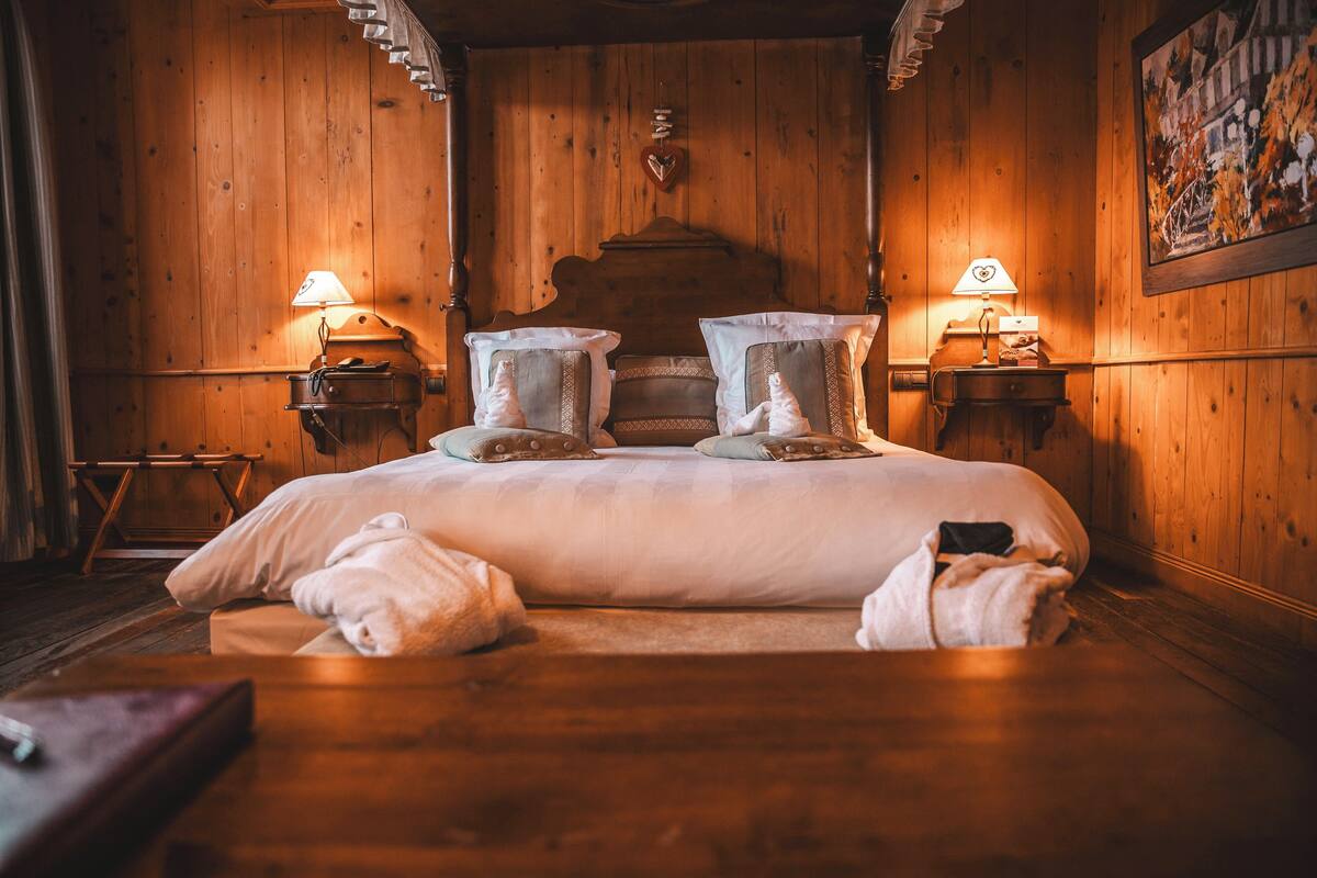A wooden room with a large bed, two bedside lamps, and a wooden headboard.
