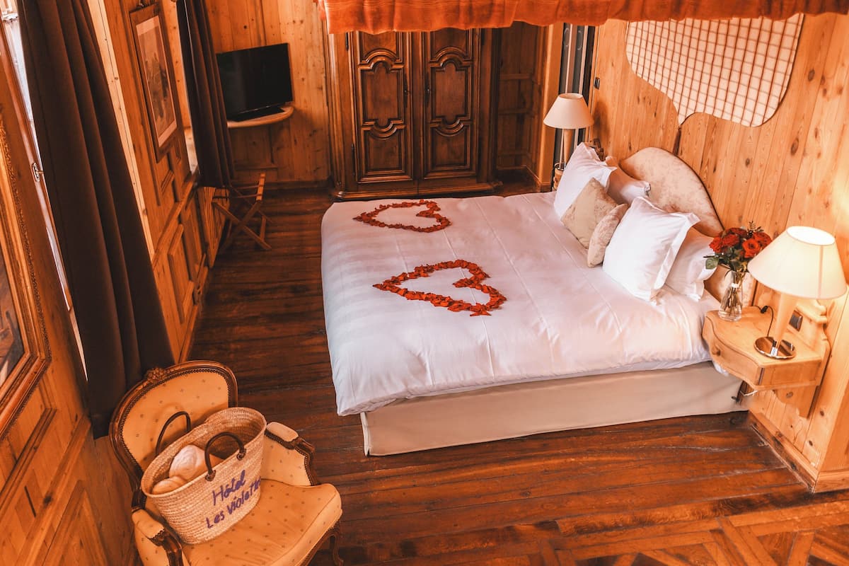A wooden room with a bed, a television, and a wicker chair.