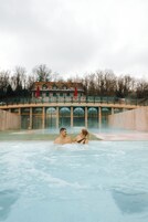 Una piscina techada, una piscina al aire libre, sombrillas
