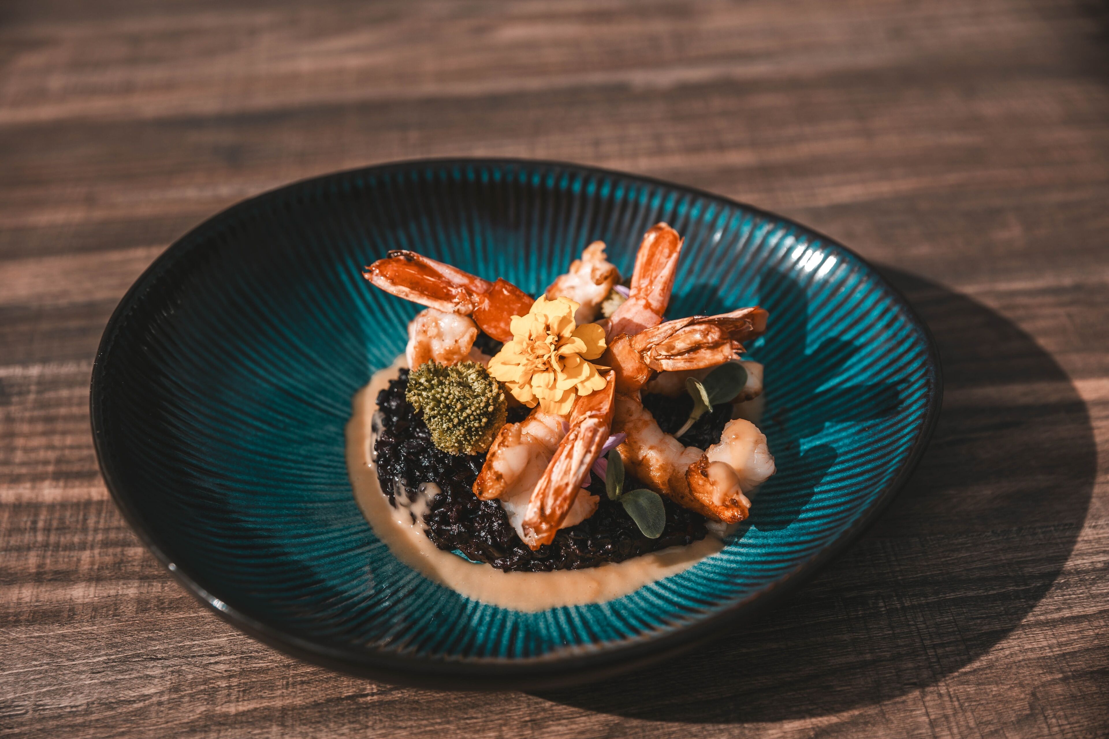 A plate of food with shrimp and other ingredients on a dark blue plate.