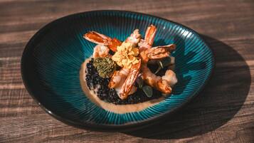 A plate of food with shrimp and other ingredients on a dark blue plate.