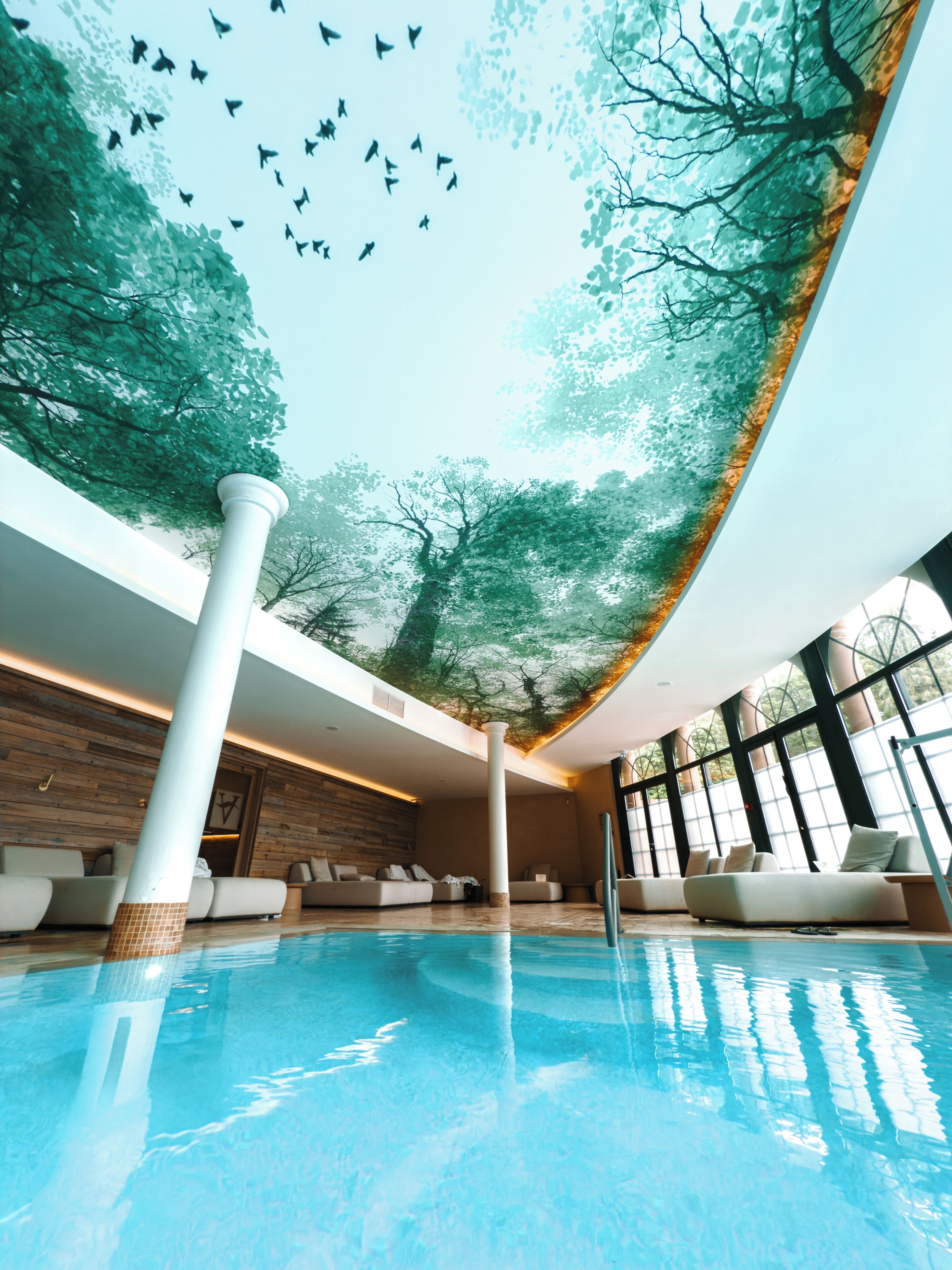 Una piscina techada, una piscina al aire libre, sombrillas