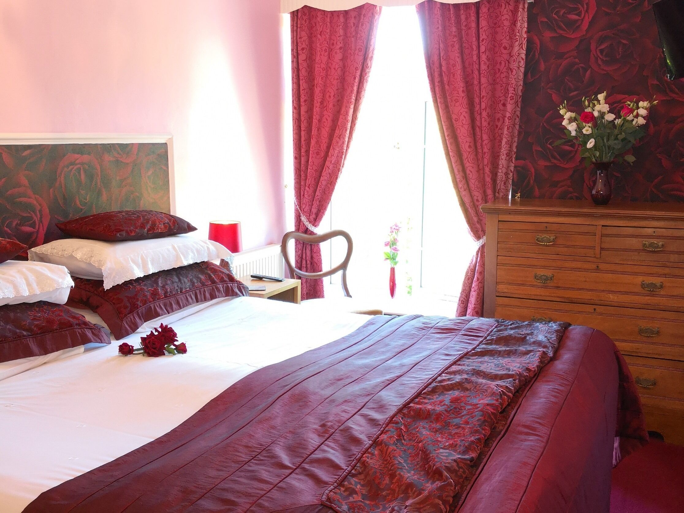 A bedroom with a large bed, a wooden dresser, and a chair.
