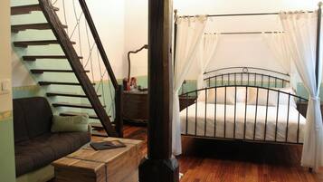 A bedroom with a wooden staircase, a bed with a metal frame, and a wooden chest of drawers.