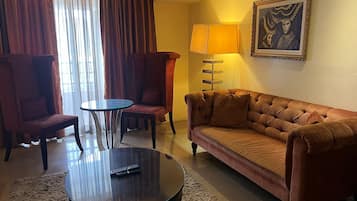 Une chambre d’hôtel avec un canapé, deux fauteuils, une table basse et une lampe.