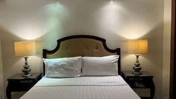 A hotel room with a large bed, two bedside lamps, and a headboard.