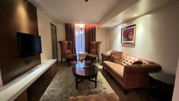 Una sala de estar moderna con un televisor de pantalla plana, un sofá, dos sillones, una mesa de centro y una alfombra.