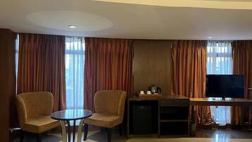 Une chambre d’hôtel avec un coin salon, une télévision et une petite kitchenette.