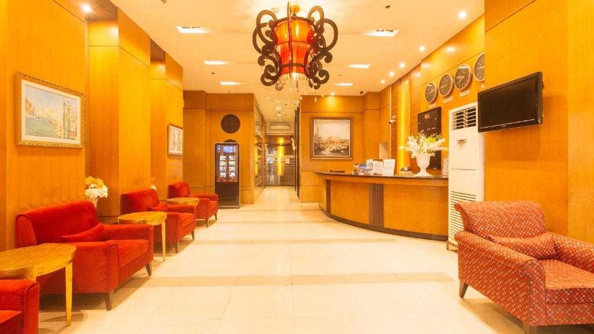 A hotel lobby with red seating, a reception desk, and a chandelier.