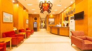 A hotel lobby with red seating, a reception desk, and a chandelier. - Palette Torre Venezia Suites (Quezon City)