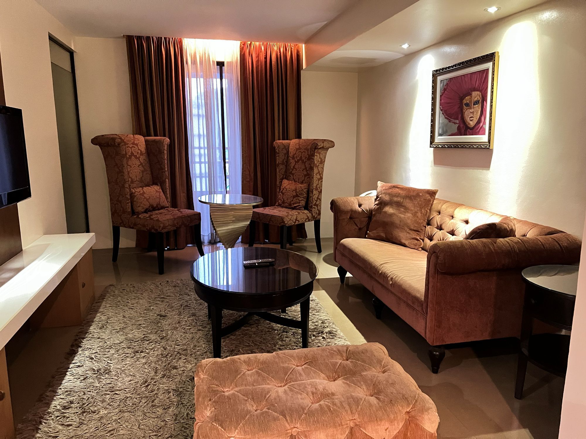 A living room with a sofa, two armchairs, a coffee table, a TV, and a framed picture on the wall.