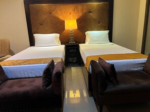 A hotel room with two beds, a nightstand, a lamp, and two armchairs. - Palette Torre Venezia Suites (Quezon City)