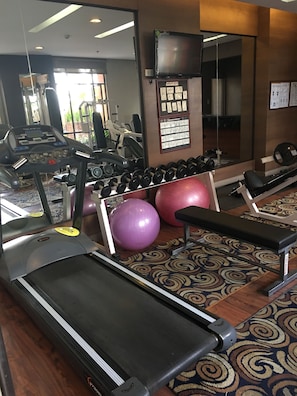 A gym with treadmills, dumbbells, exercise balls, and a bench.