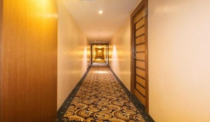 A hotel hallway with a patterned carpet and wooden doors.