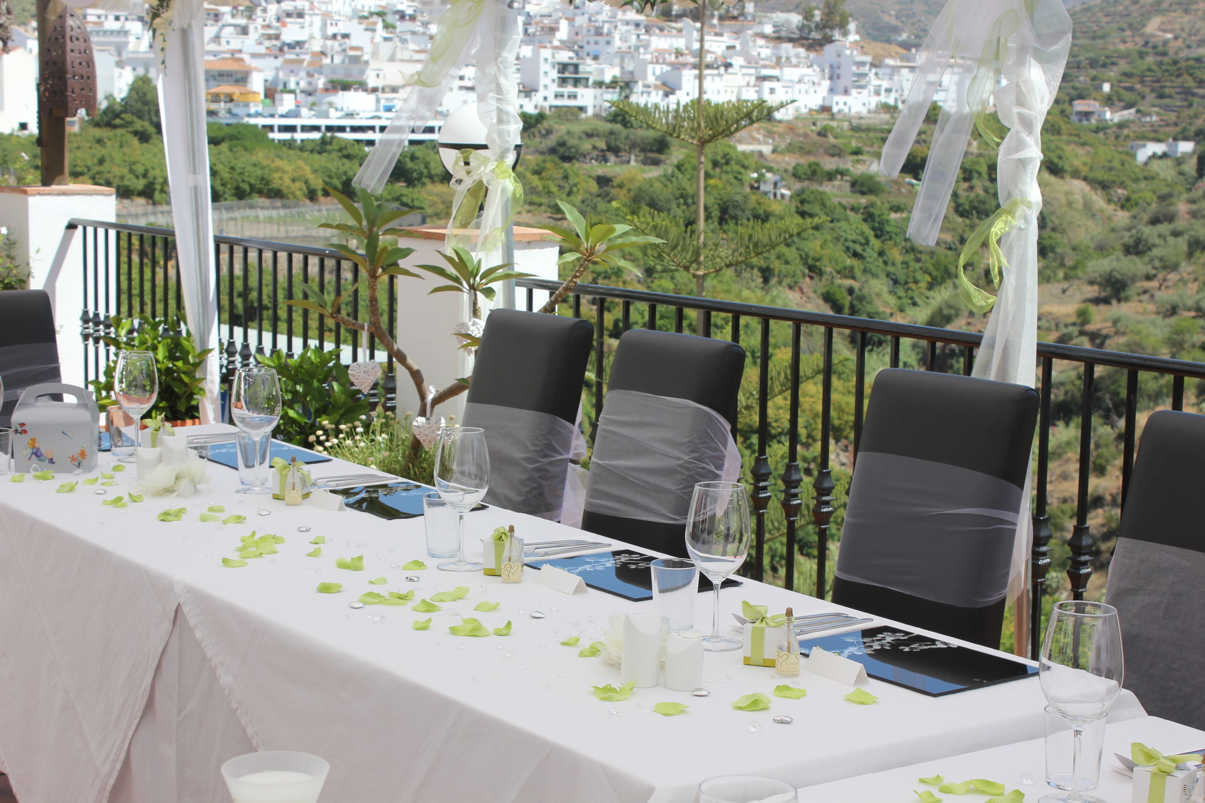 A table set for a wedding with chairs, a white tablecloth, and a view of a cityscape.