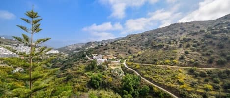 A mountainous landscape with a winding road leading to a cluster of buildings.