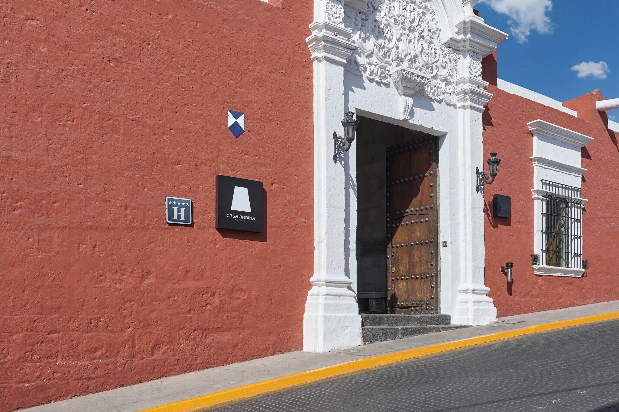Un edificio rojo con puerta blanca, un cartel que dice 'CASA ANDINA' y un farol.