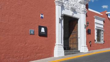 Un edificio rojo con puerta blanca, un cartel que dice 'CASA ANDINA' y un farol.