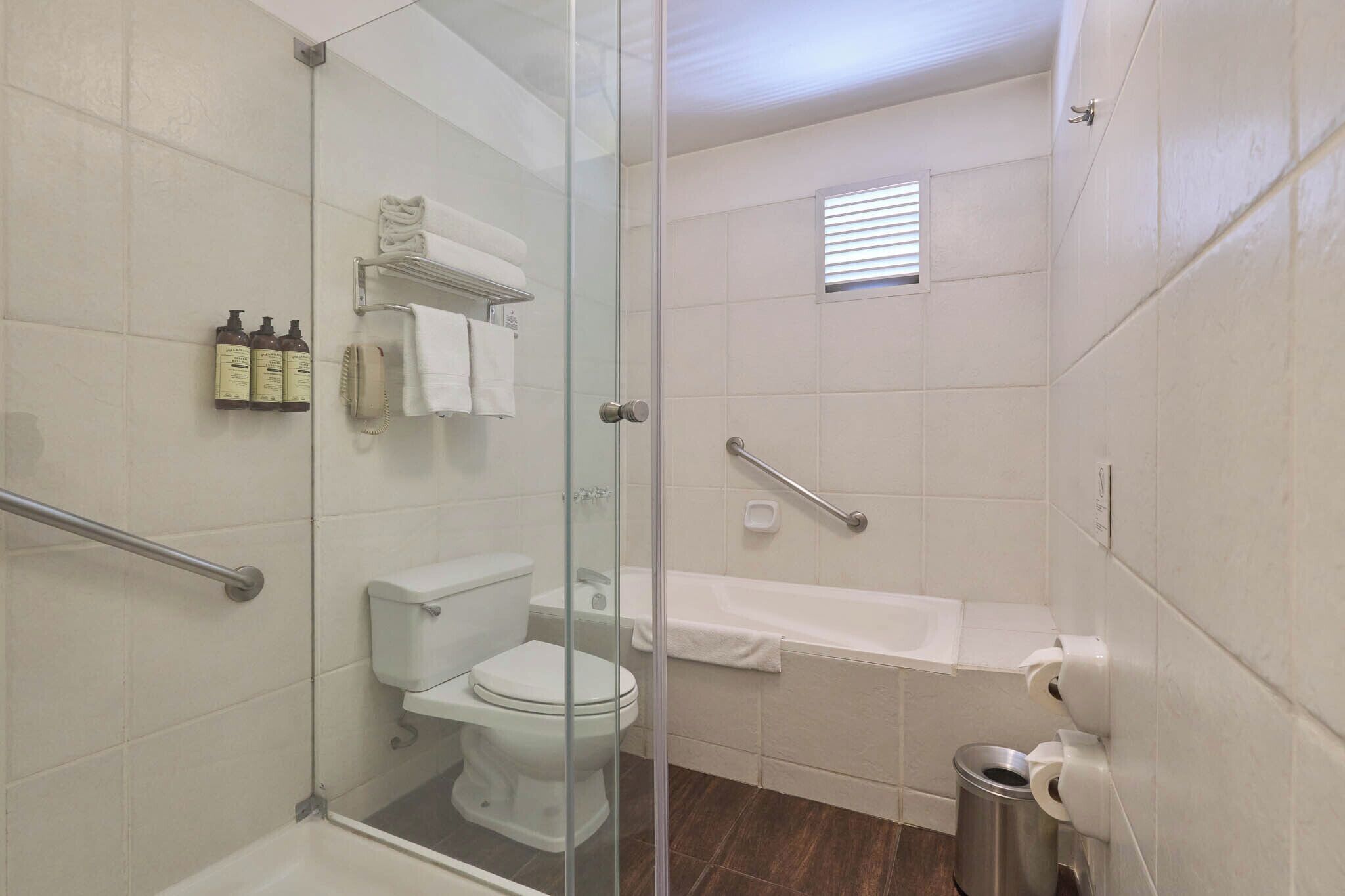 Un baño con cabina de ducha de vidrio, inodoro, bañera y secador de manos.