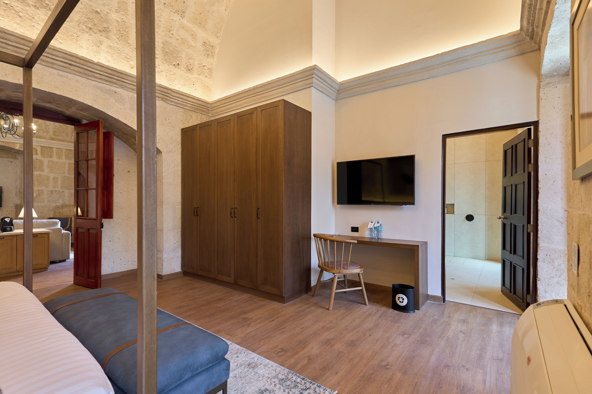 A bedroom with a bed, a desk, a chair, and a TV.