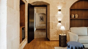 A hallway with a wooden door, a lamp, a sofa, and a stone wall. - Casa Andina Premium Arequipa (Arequipa)