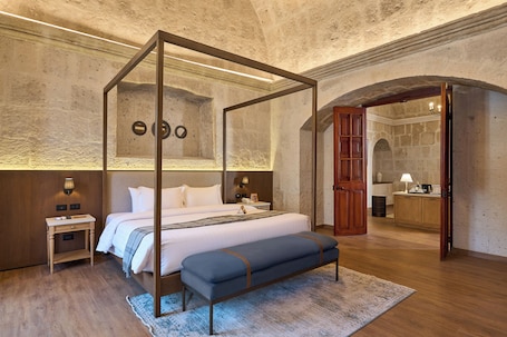 A bedroom with a four-poster bed, a bedside table, a bench, a nightstand, and a mirror.