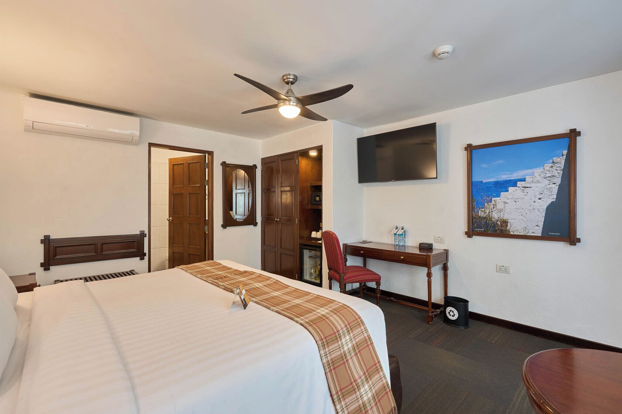 Habitación de hotel con cama, escritorio, silla y un cuadro en la pared.