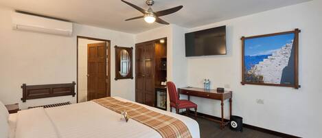 Habitación de hotel con cama, escritorio, silla y un cuadro en la pared.