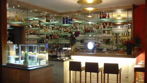 A bar area with wooden stools, shelves of bottles, and a display case with fruits. - Hotel Rosengarten Kehl (Kehl)